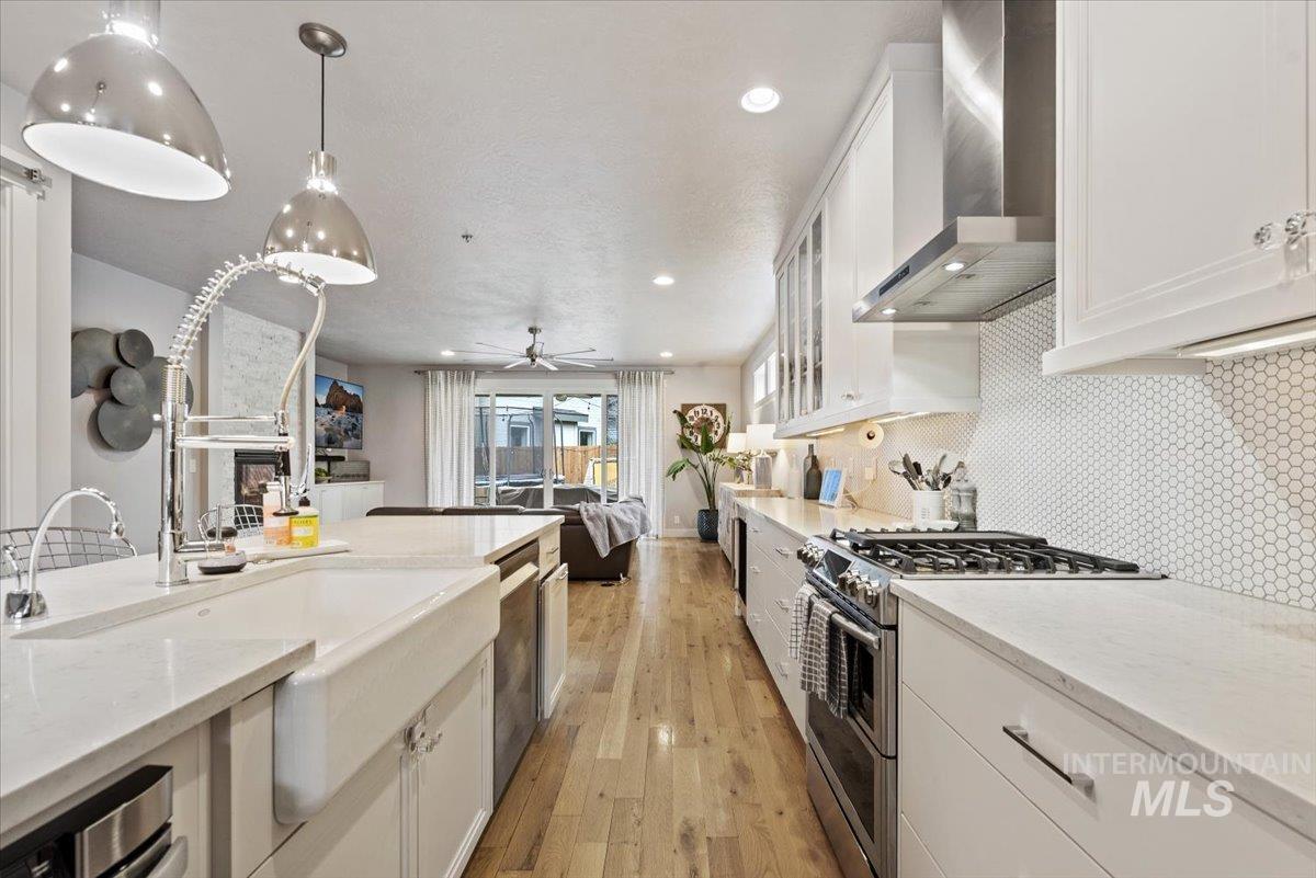2616 West Neff Street Boise, ID 83702 - Photo 8 of 36 Kitchen with white cabinetry, stainless steel appliances, wall chimney exhaust hood, light wood-type flooring, and light stone countertops
