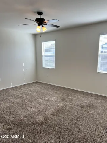 an empty room with windows and fan