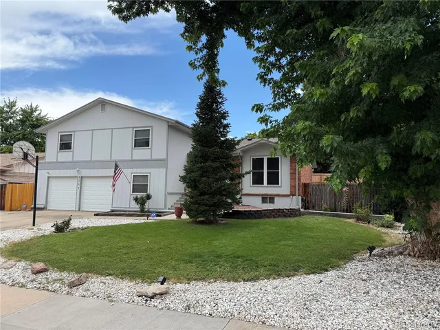 a front view of a house with a garden and trees