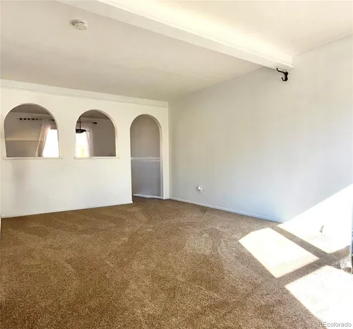 a view of an empty room with window and dresser