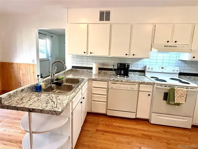 a kitchen with kitchen island granite countertop a sink a stove and white cabinets