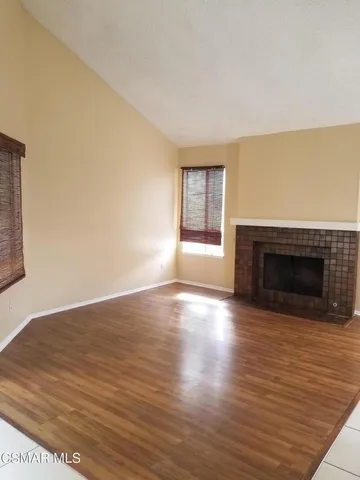 a view of empty room with wooden floor and fireplace