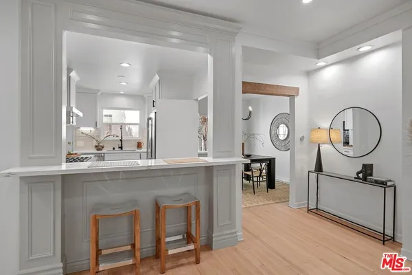 a very nice looking kitchen with granite countertop a stove a sink and a dining table with wooden floors