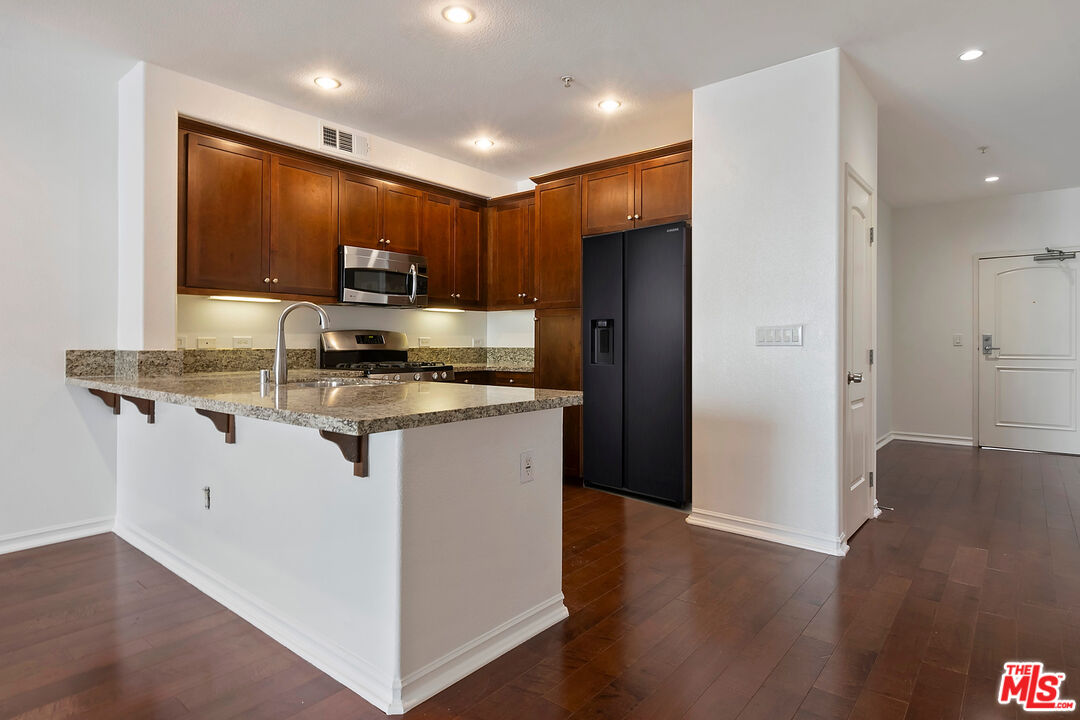629 Traction Avenue, Unit 507 Los Angeles, CA 90013 - Photo 12 of 52 a kitchen with kitchen island granite countertop stainless steel appliances stove refrigerator and microwave