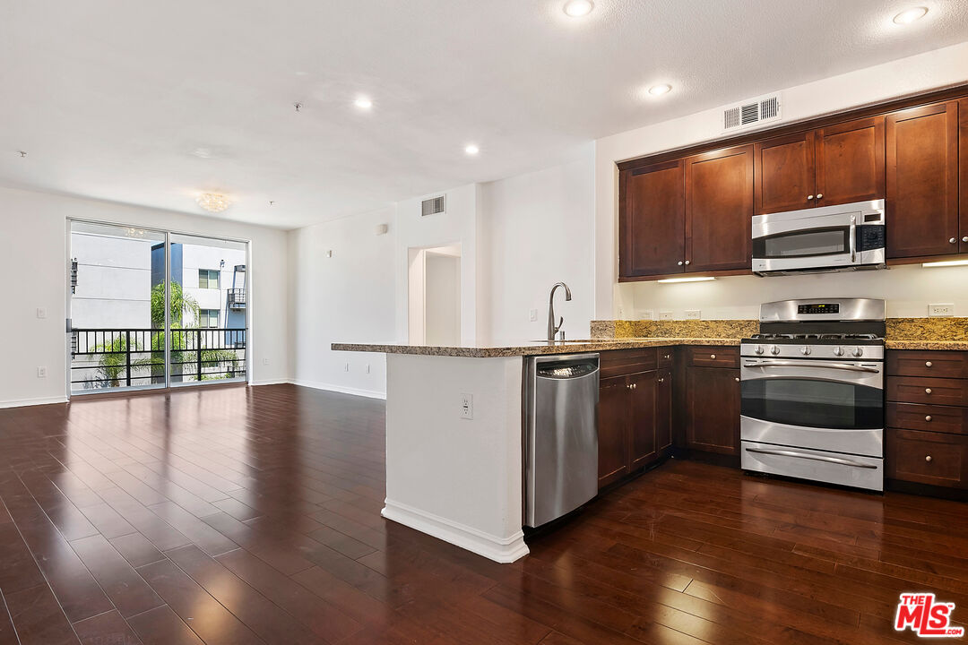 629 Traction Avenue, Unit 507 Los Angeles, CA 90013 - Photo 14 of 52 a kitchen with stainless steel appliances kitchen island granite countertop a stove a sink and a microwave