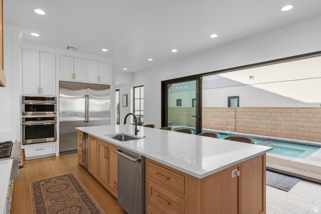 5367 Cyan Lane St. George, UT 84790 - Photo 25 of 49 Spacious kitchen featuring a large island with a countertop, integrated sink, and seating, alongside wood-finish flooring