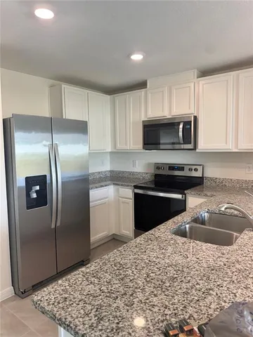 a kitchen with a refrigerator sink and cabinets