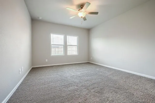 an empty room with a window and a ceiling fan