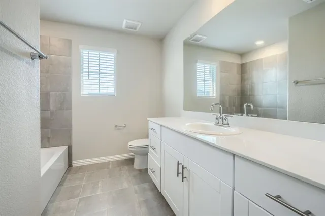 a bathroom with a granite countertop sink a toilet and a shower