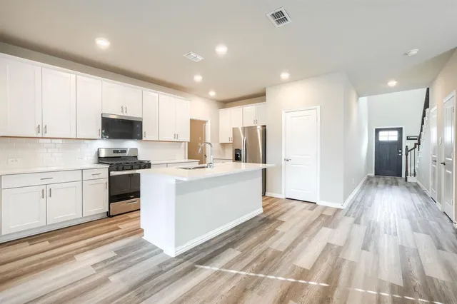 a kitchen with granite countertop a refrigerator stove top oven and sink