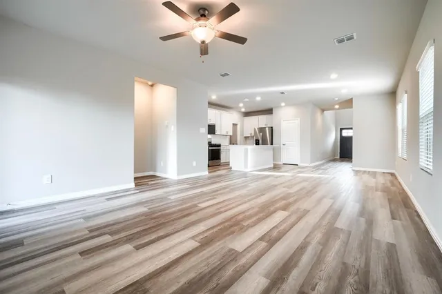 a view of a big room with wooden floor and a kitchen