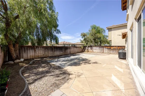 a view of a backyard with large trees and wooden fence
