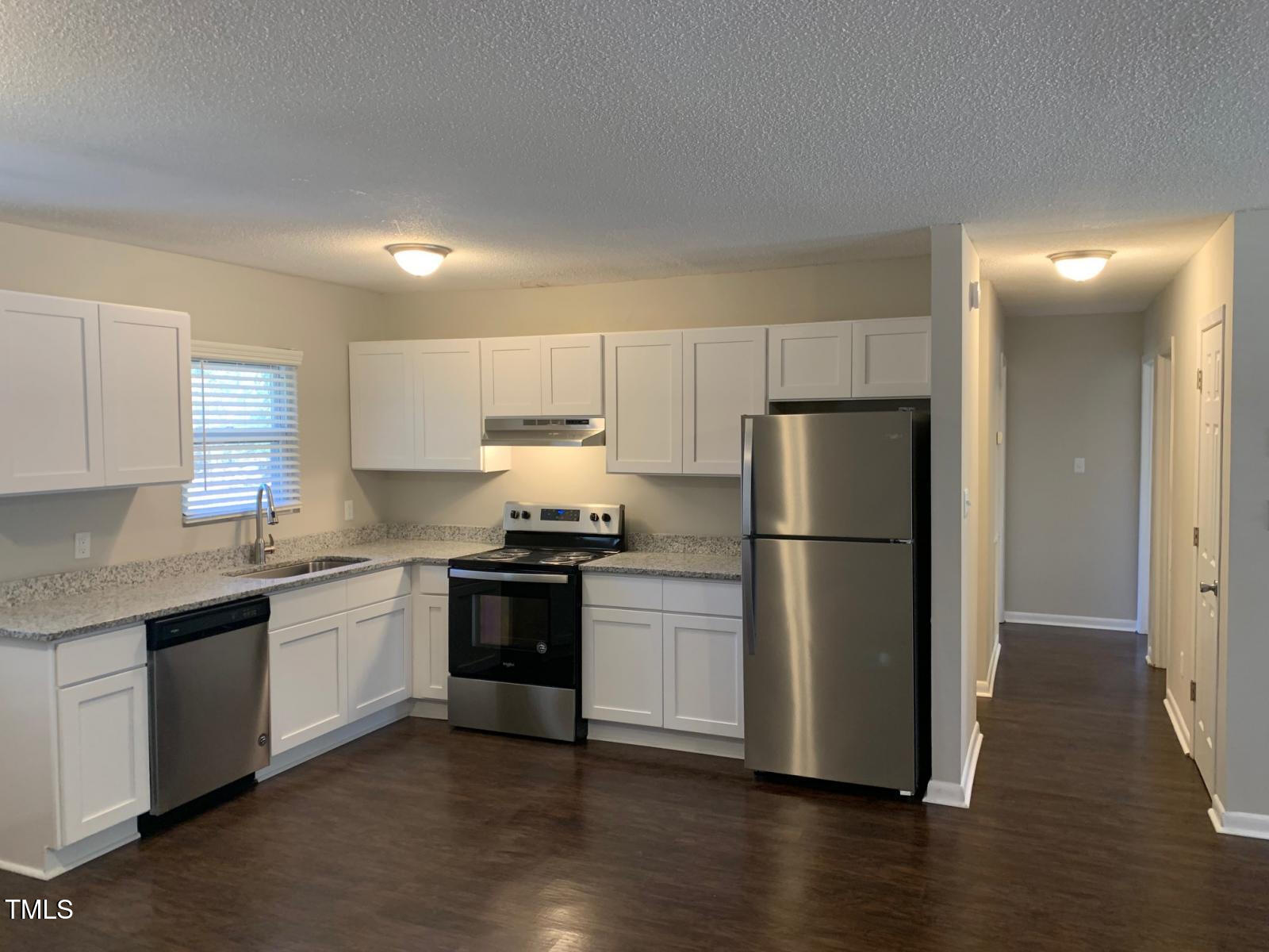 3604 Bowling Drive Raleigh, NC 27606 - Photo 5 of 10 a kitchen with a sink a refrigerator and white cabinets