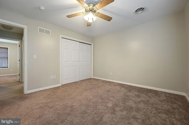 an empty room with closet and a chandelier fan