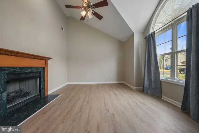 an empty room with wooden floor fireplace and windows