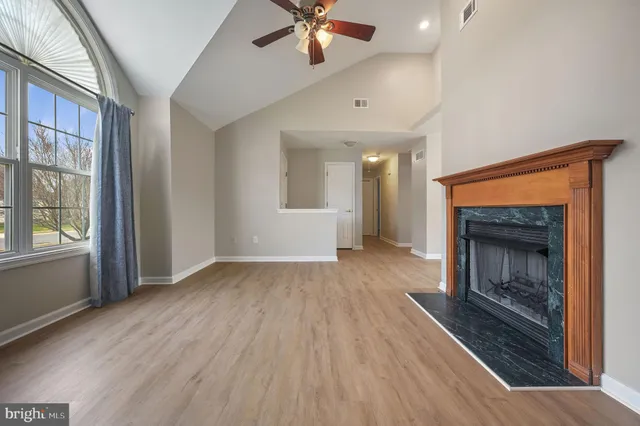 a view of an empty room with wooden floor fireplace and a window