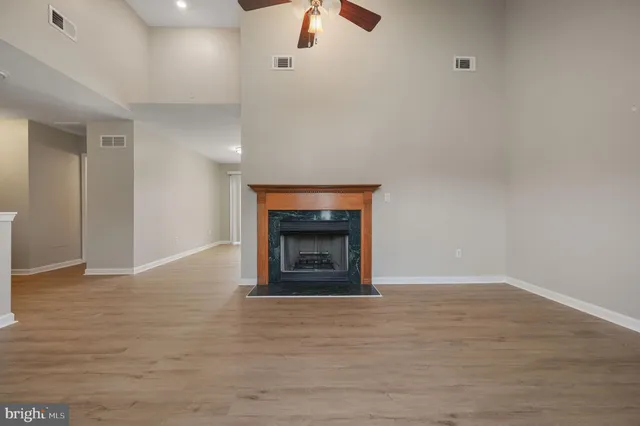 a view of an empty room with a fireplace and a chandelier fan