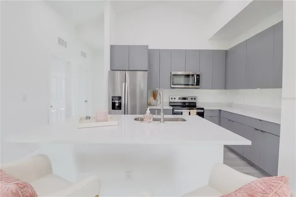 a kitchen with granite countertop a refrigerator sink and white cabinets