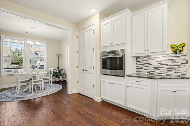 a kitchen with white cabinets and wooden floor