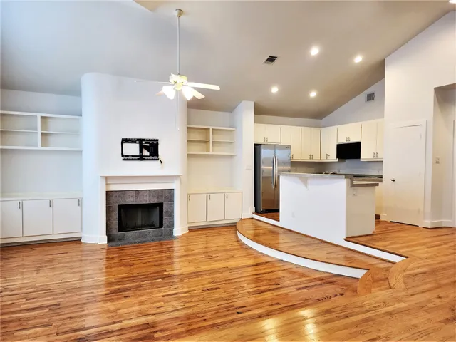 a living room with stainless steel appliances furniture wooden floor and a kitchen view