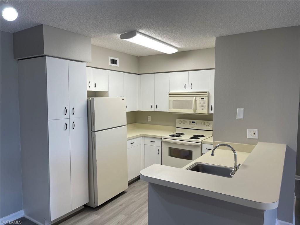 13555 Eagle Ridge Drive, Unit 925 Fort Myers, FL 33912 - Photo 4 of 15 a kitchen with a refrigerator a stove a sink and a refrigerator