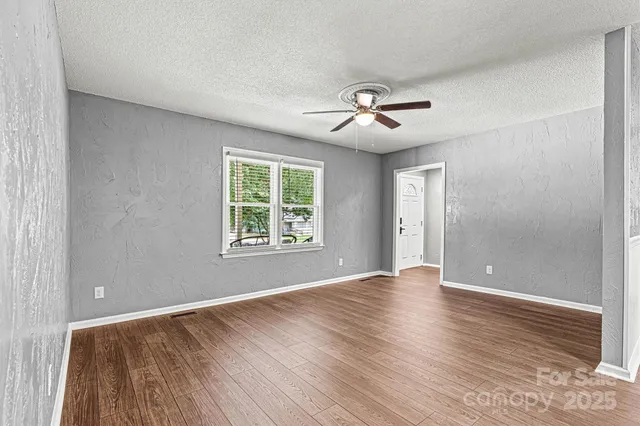 a view of an empty room with a window and wooden floor