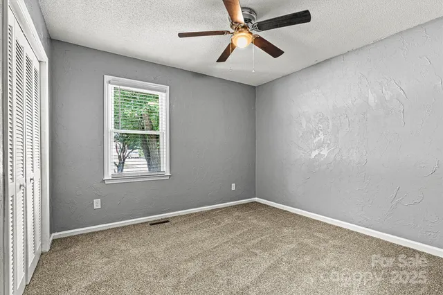 an empty room with a window and a fan