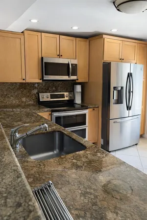 a kitchen with granite countertop a refrigerator and a sink