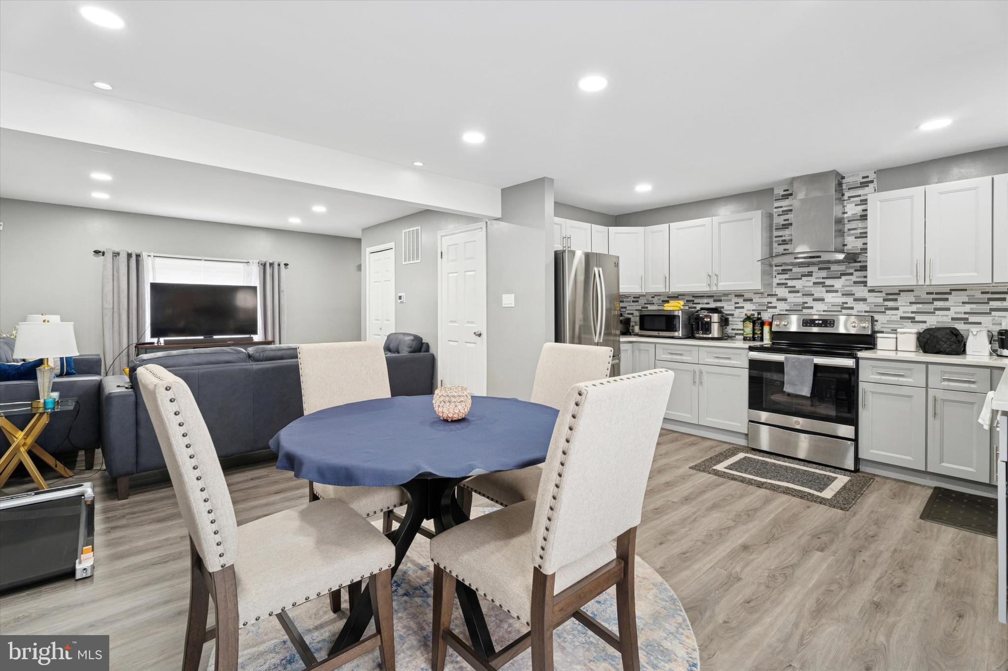 8319 Woolston Avenue Philadelphia, PA 19150 - Photo 12 of 30 a kitchen with stainless steel appliances kitchen island granite countertop a dining table chairs refrigerator and microwave