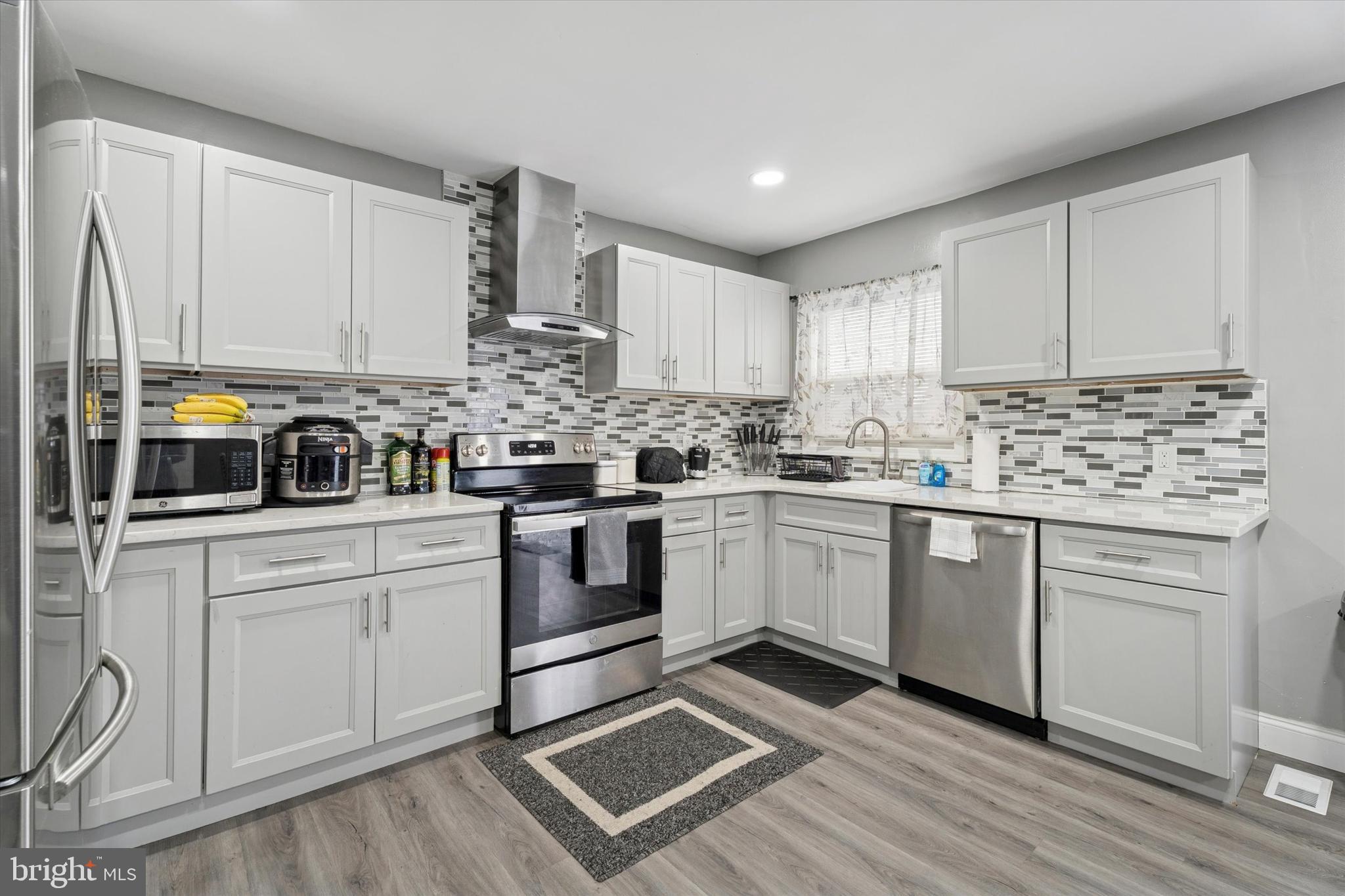 8319 Woolston Avenue Philadelphia, PA 19150 - Photo 4 of 30 a kitchen with granite countertop white cabinets stainless steel appliances a sink and a window