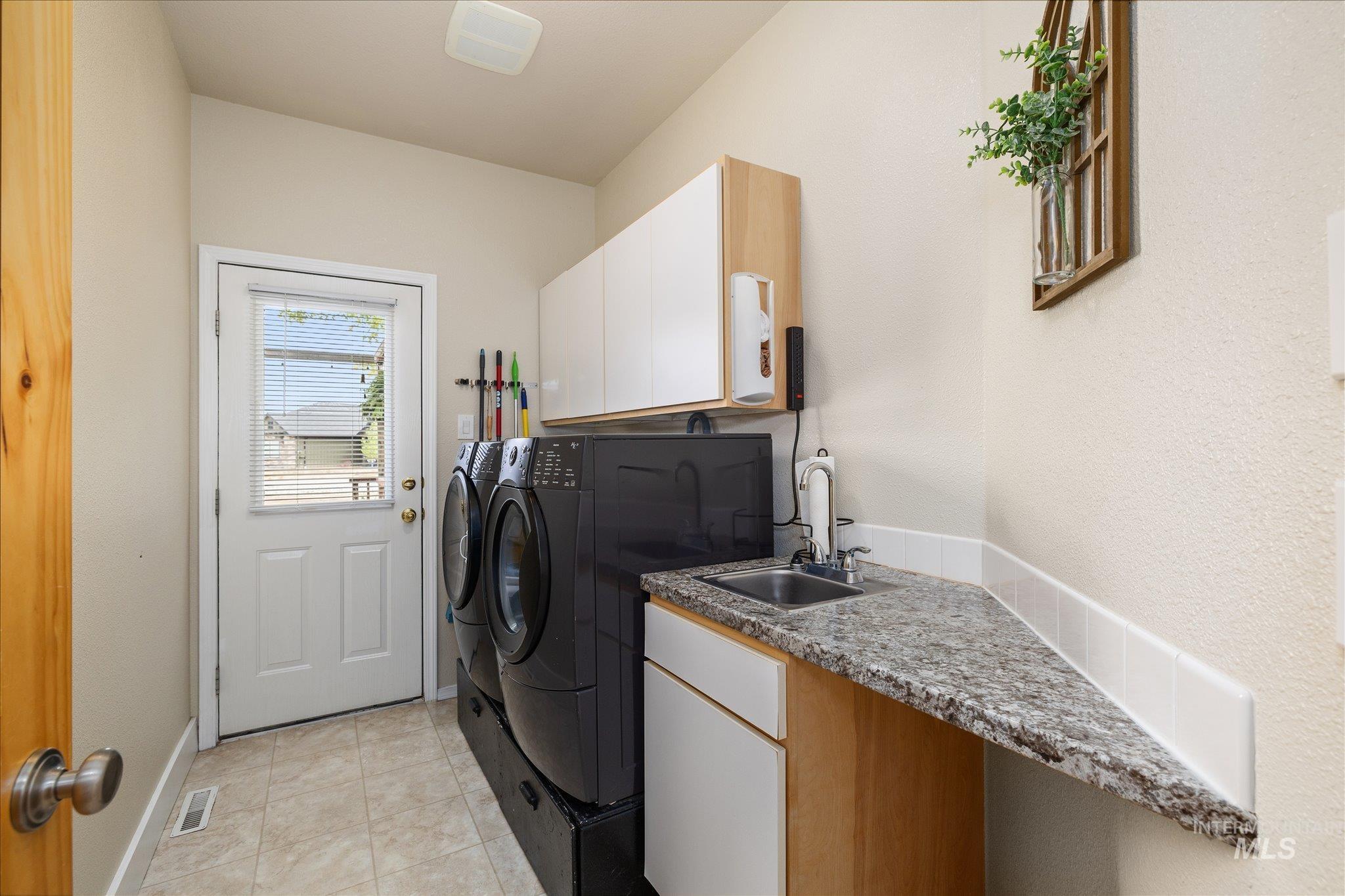 1140 Edgemont Road Emmett, ID 83617 - Photo 26 of 50 Dedicated laundry space featuring a utility sink with a granite-style countertop, white cabinetry, and tiled flooring