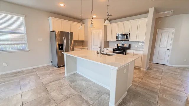 a kitchen that has a refrigerator a sink and a stove top oven