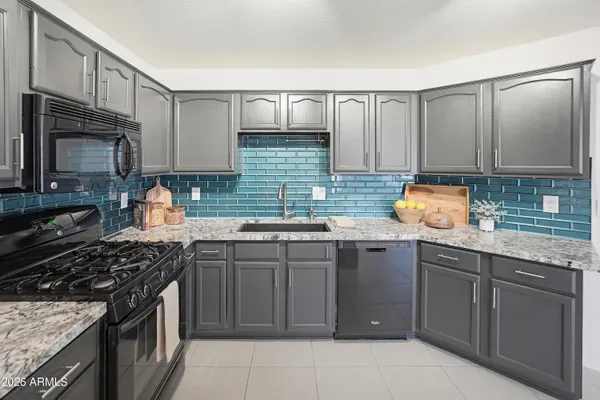 a kitchen with stainless steel appliances granite countertop a sink stove refrigerator and cabinets