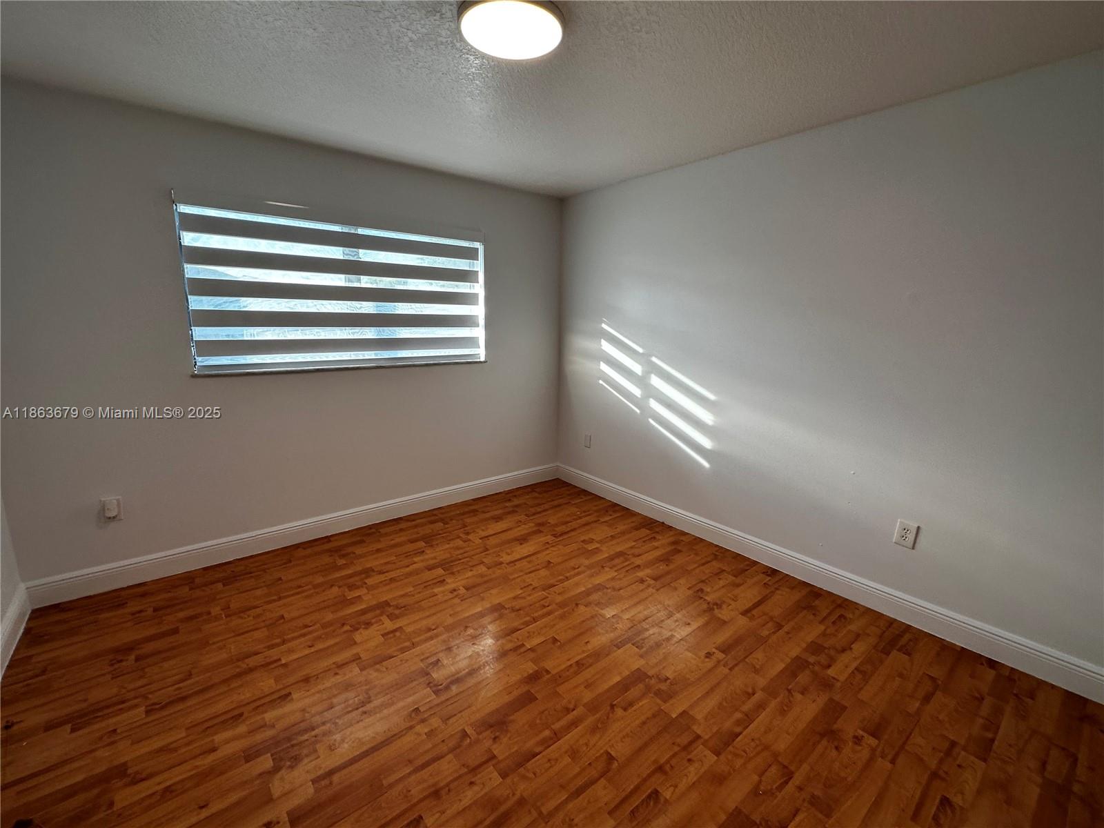 13440 Southwest 62nd Street, Unit G101 Miami, FL 33183 - Photo 17 of 23 a view of an empty room with wooden floor and a window