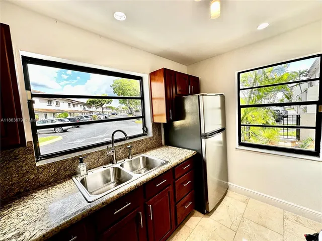 a kitchen with granite countertop a sink and a refrigerator