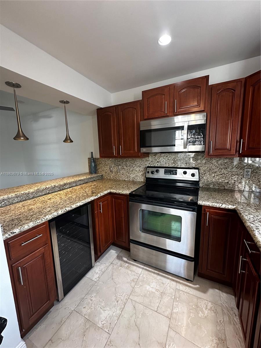 13440 Southwest 62nd Street, Unit G101 Miami, FL 33183 - Photo 8 of 23 a kitchen with granite countertop wooden cabinets and stainless steel appliances