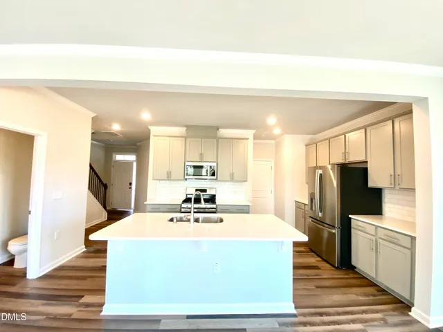a room with kitchen island stainless steel appliances a sink and a refrigerator