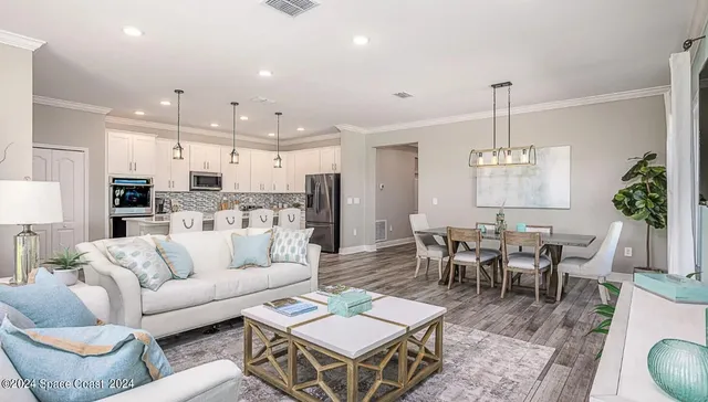 a living room with furniture kitchen view and a chandelier