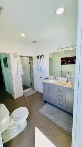 a bathroom with a granite countertop sink mirror vanity and toilet