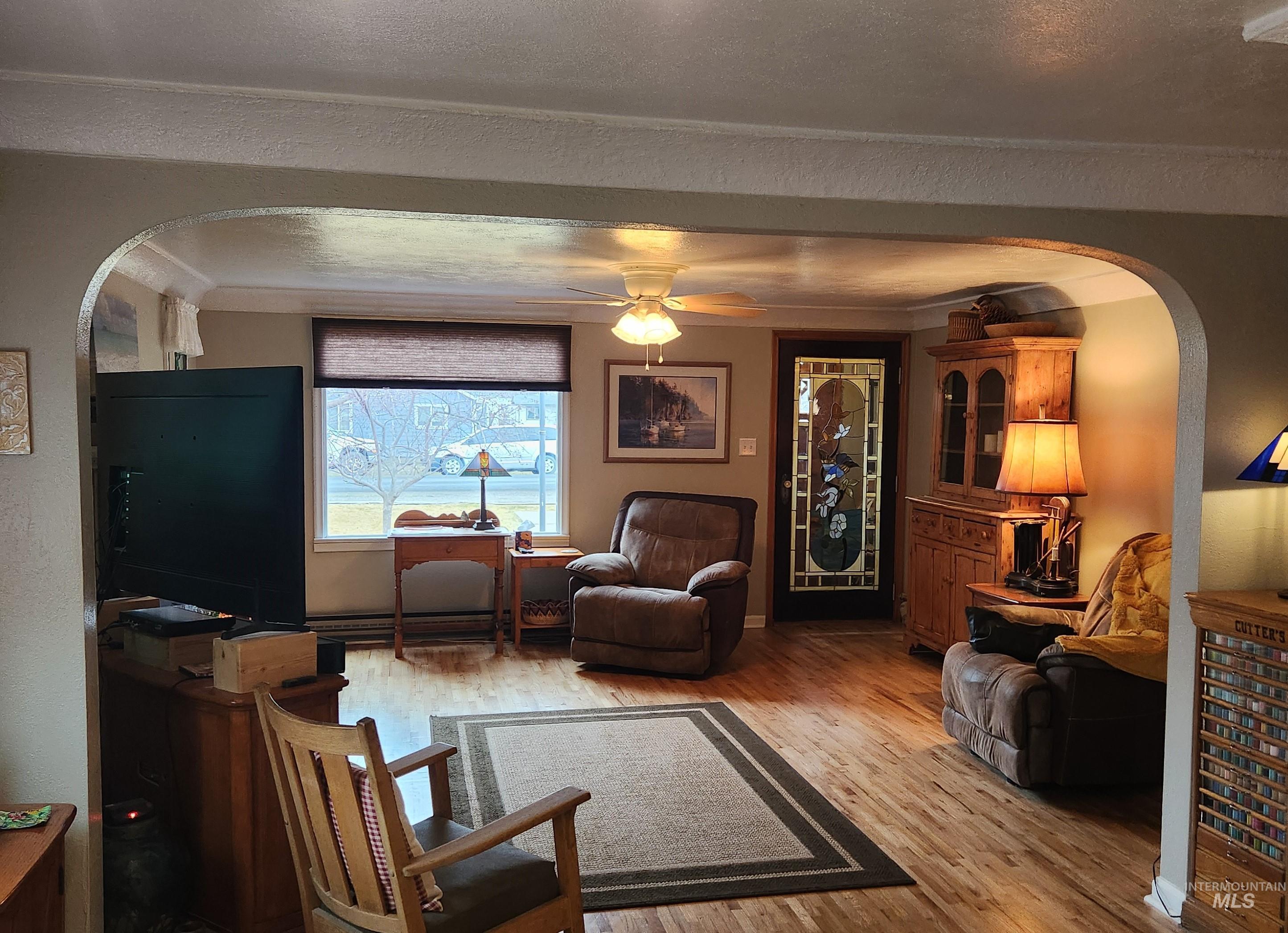 1105 Nevada Street Gooding, ID 83330 - Photo 12 of 26 Living area featuring arched walkways, a ceiling fan, light wood-style flooring, and a textured wall
