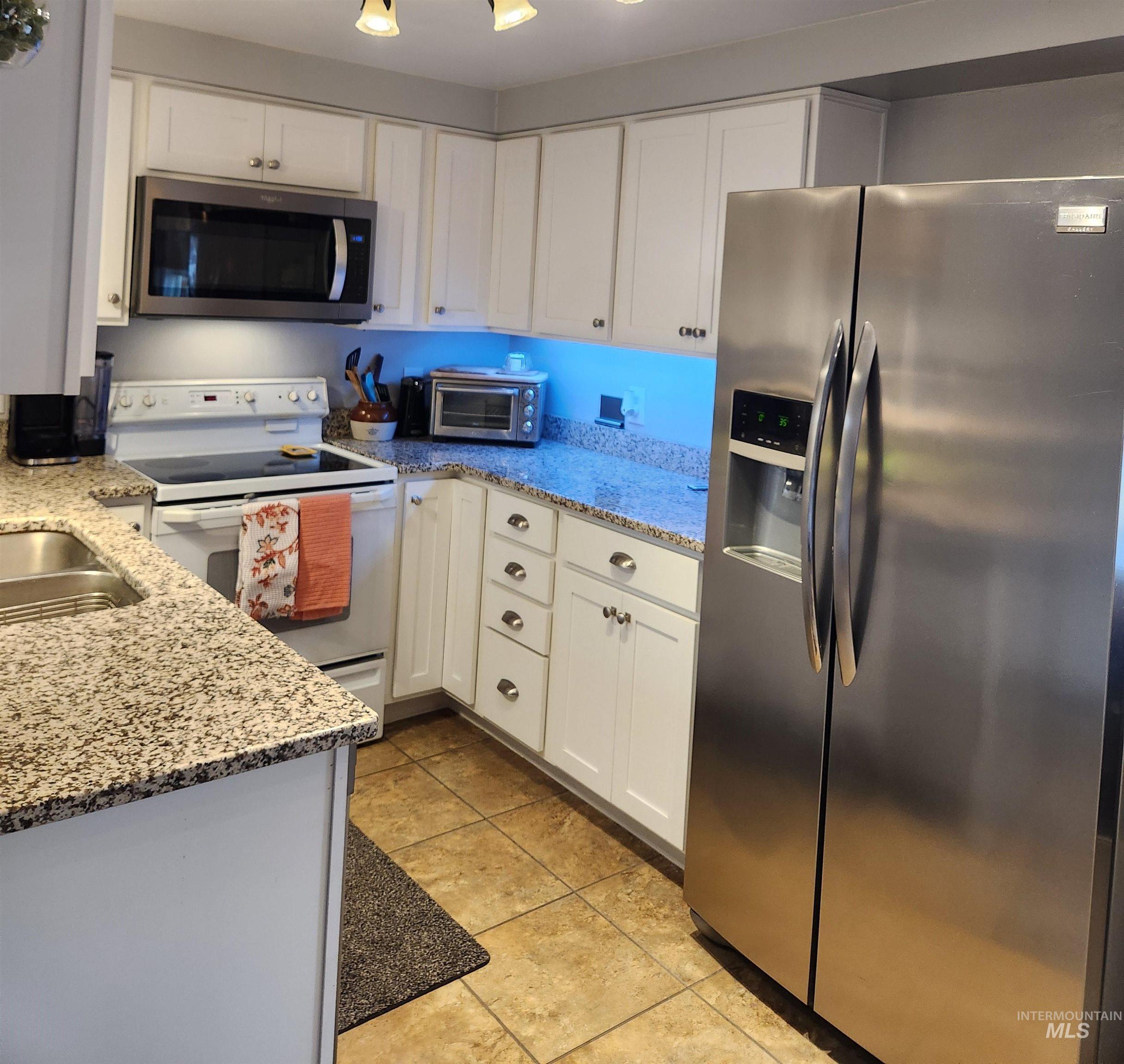 1105 Nevada Street Gooding, ID 83330 - Photo 9 of 26 Kitchen with stainless steel appliances, light stone counters, and white cabinets