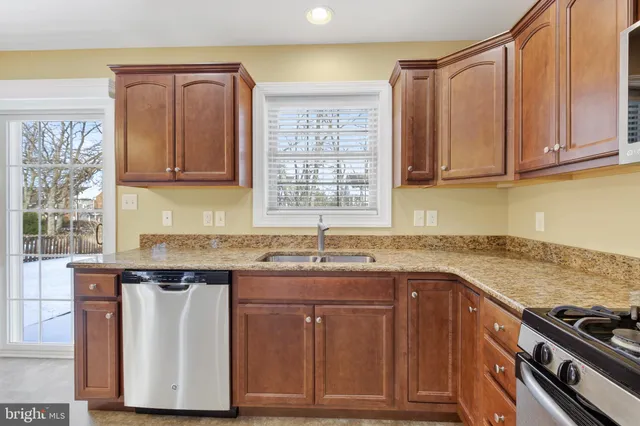 a kitchen with granite countertop a sink a stove and cabinets