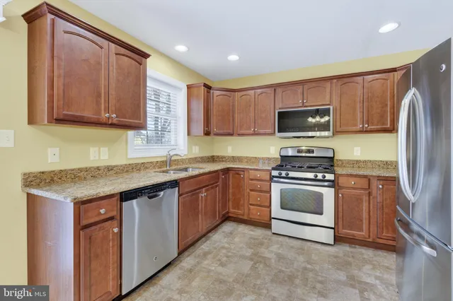 a kitchen with stainless steel appliances granite countertop a stove a sink dishwasher a refrigerator and a microwave oven