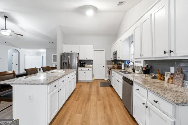 a large kitchen with stainless steel appliances granite countertop a lot of counter space and wooden floors