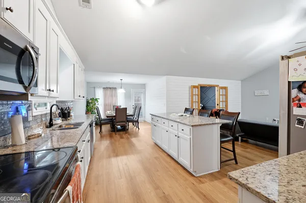 a kitchen with stainless steel appliances granite countertop a stove top oven a sink dishwasher and cabinets with wooden floor