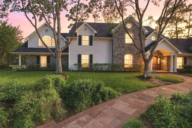 a front view of a house with a garden and trees