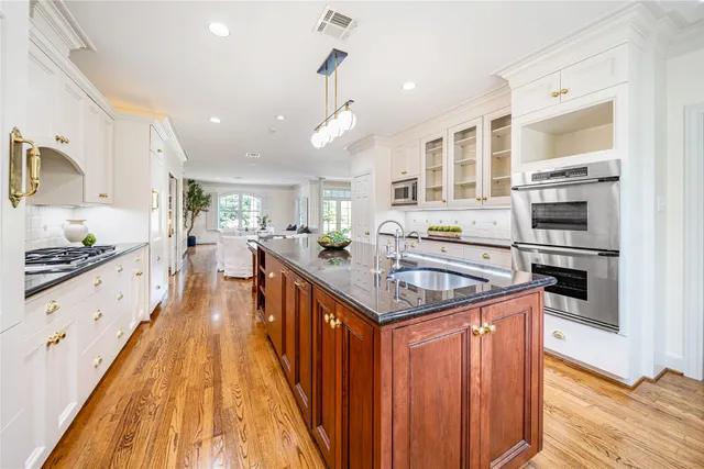 a large kitchen with stainless steel appliances a large counter space and wooden floors