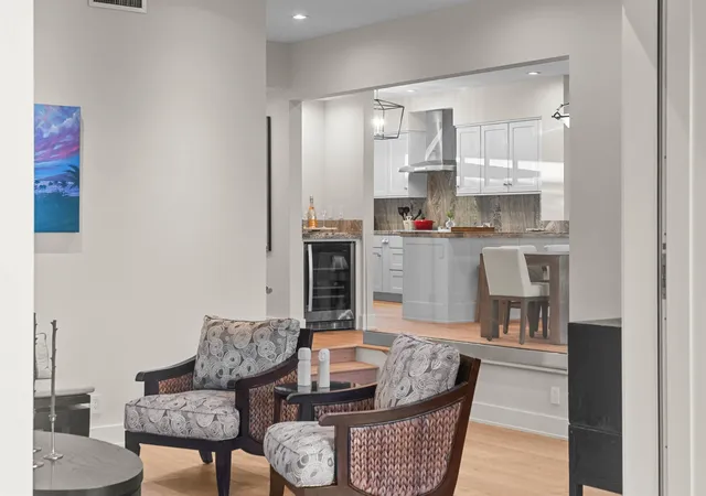 a living room with stainless steel appliances furniture and a kitchen view