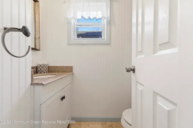 a bathroom with a granite countertop toilet sink and mirror