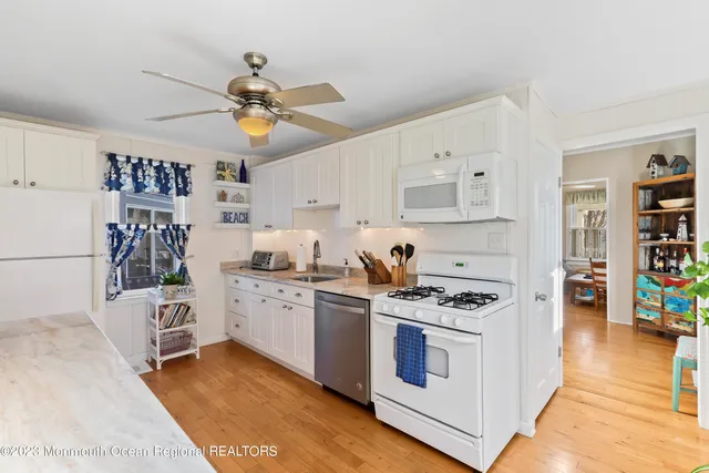 a kitchen with stainless steel appliances white cabinets and wooden floor